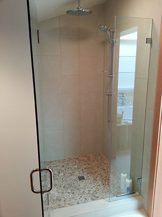 Built shower with frameless shower door and tile work.